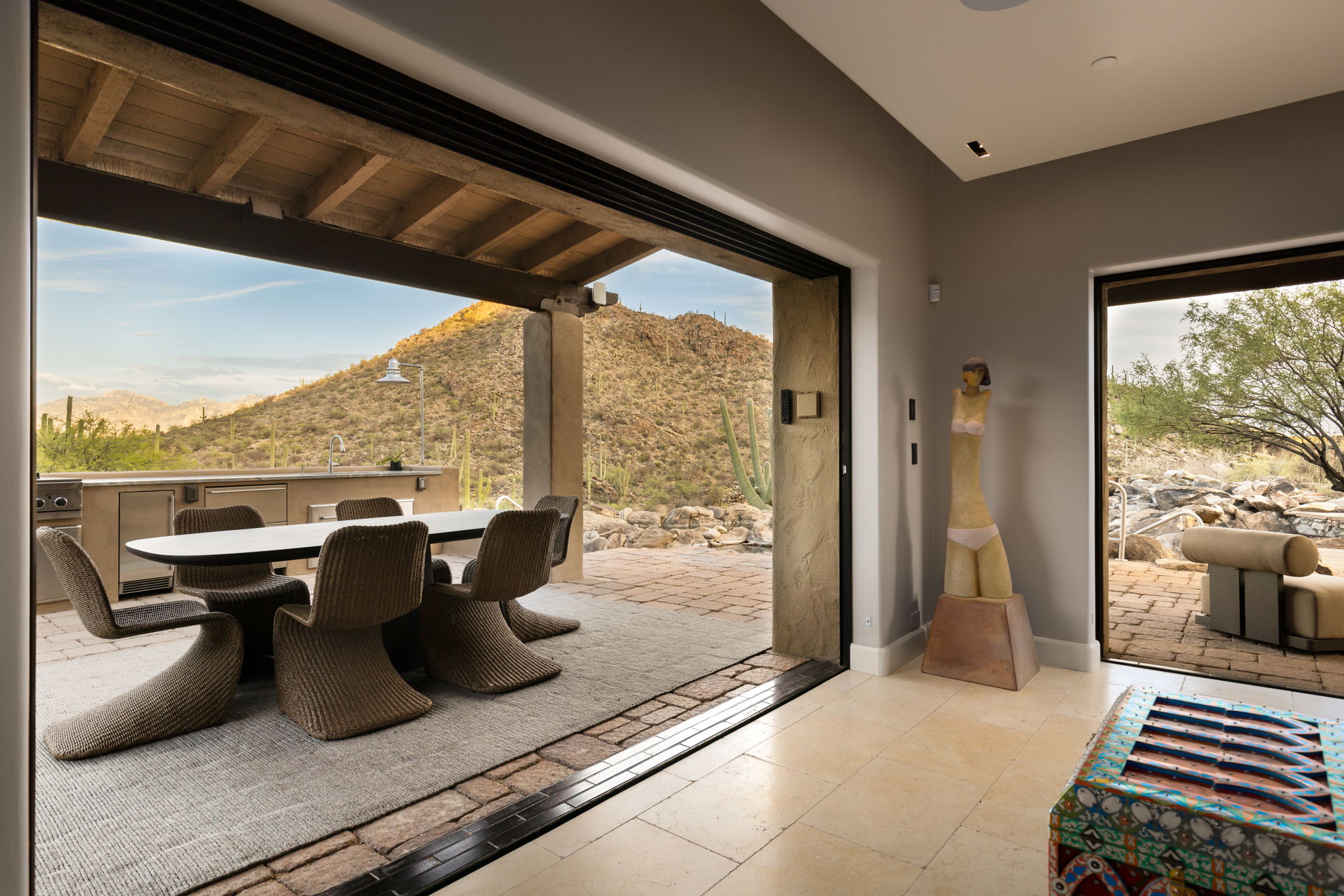 Panoramic doors folded open to the terrace, dining table and grill beyond