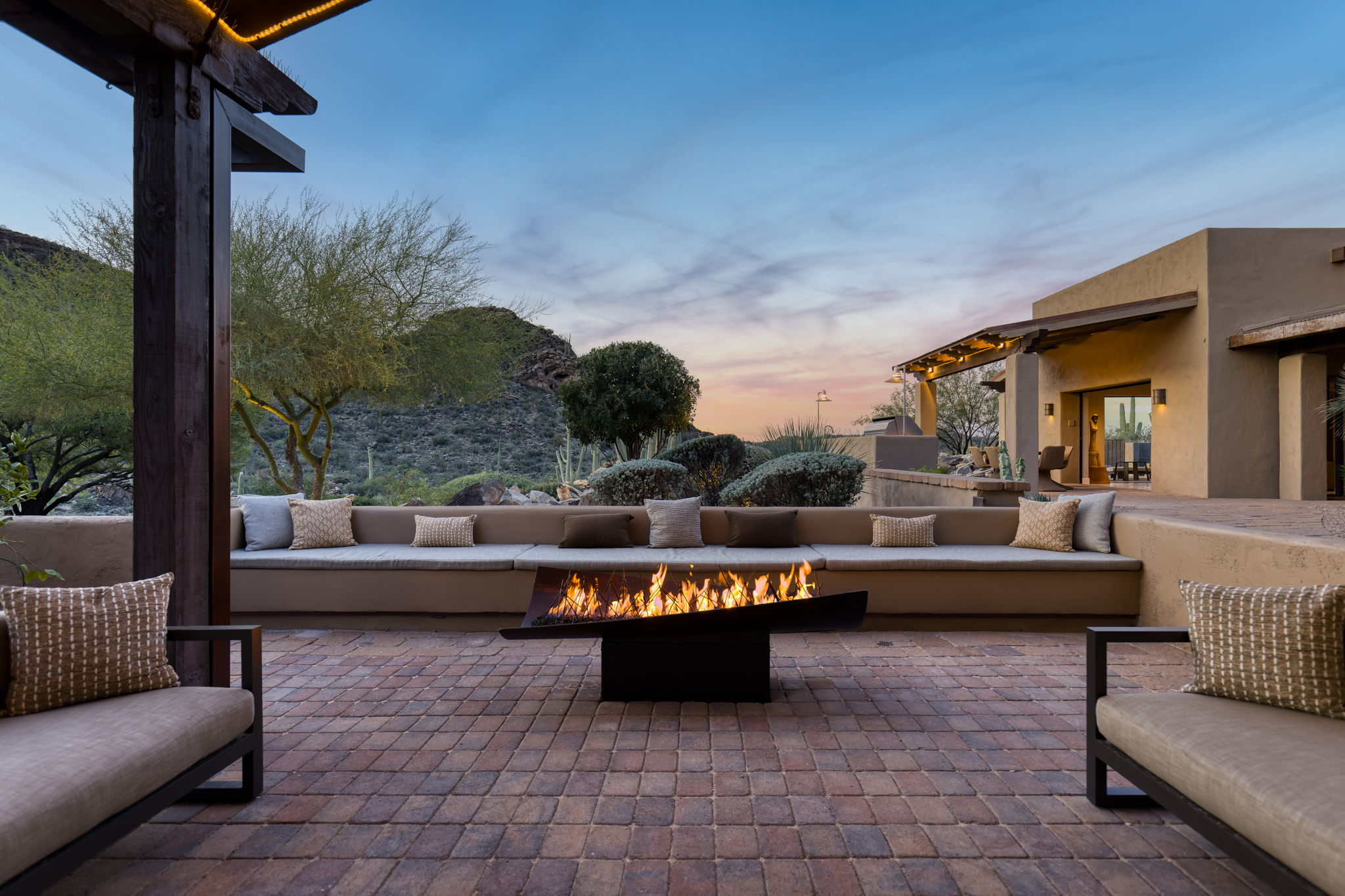 Built-in bench seating around a low fire trough at twilight
