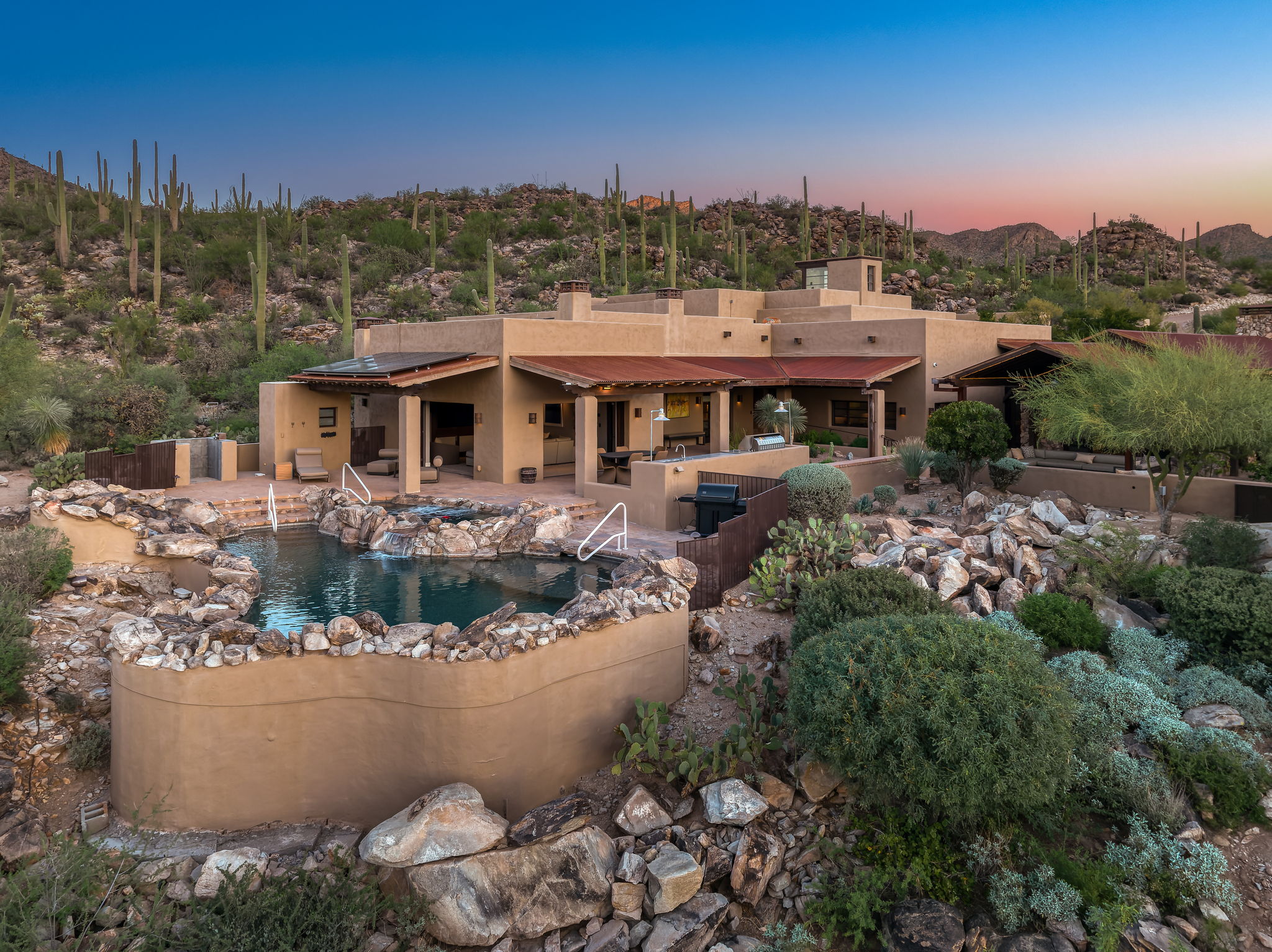 Rear elevation with pool and pueblo rooflines at dusk