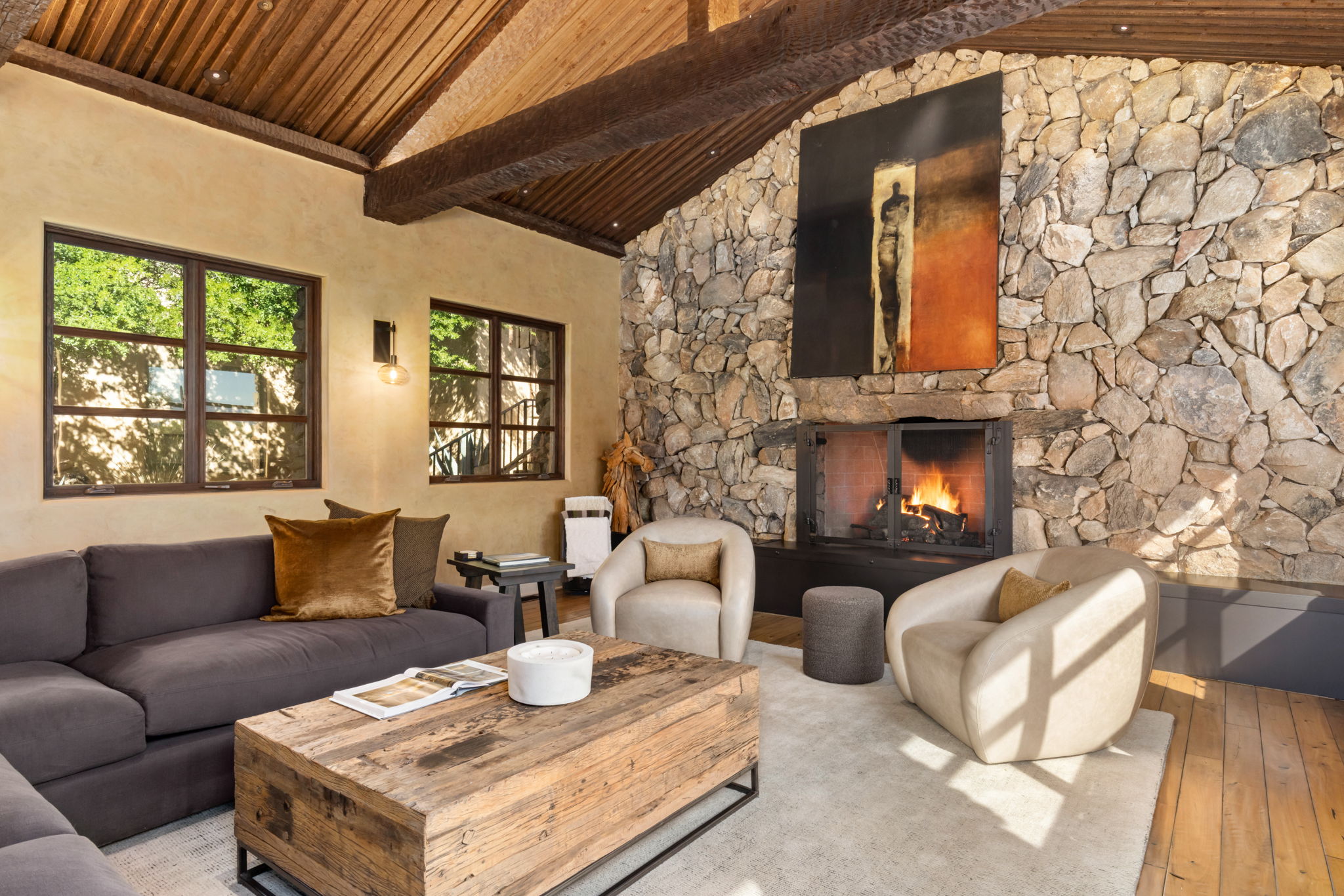 The great room with the fire lit, afternoon sun across the floor